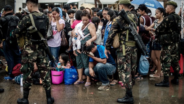 A woman comforts a crying relative as a plane leaves the Tacloban airport November 12.