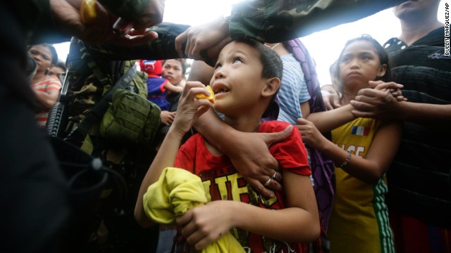 A Philippine air force officer hands out orange slices to typhoon survivors as they line up to board a military transport plane November 12 in Tacloban.