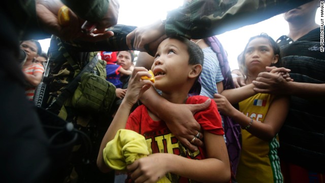 A Philippines air force officer hands out orange slices to typhoon survivors as they line up to board a military plane November 12 in Tacloban.