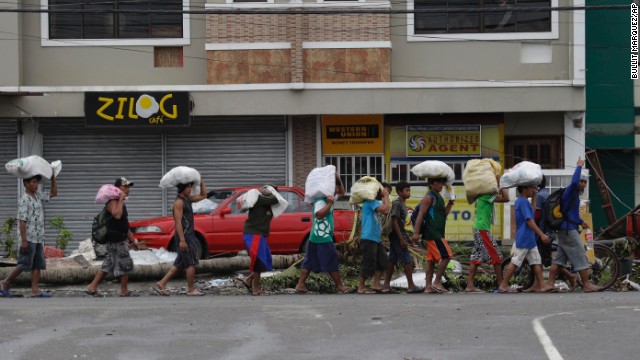 People carry sacks of goods November 12 in Tacloban.