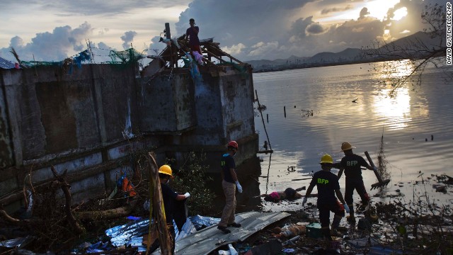 A rescue team wades into floodwater to retrieve a body in Tacloban on November 13. 