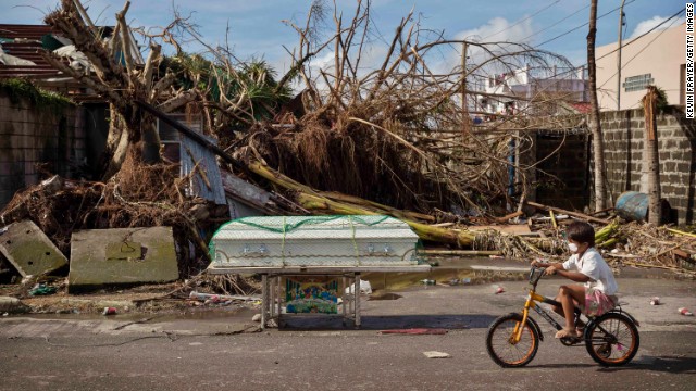 A boy cycles past a coffin left on a street in Tacloban on November 13. 