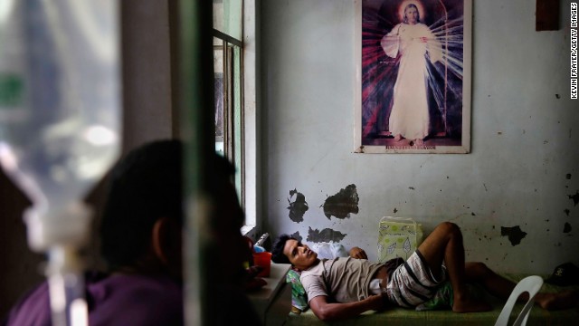 An injured man in Tacloban rests beneath a picture of Jesus Christ on November 13.