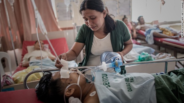 A typhoon survivor keeps her husband alive by manually pumping air into his lungs after his leg was amputated at a Tacloban hospital November 15. The hospital has been operating without power since the typhoon.
