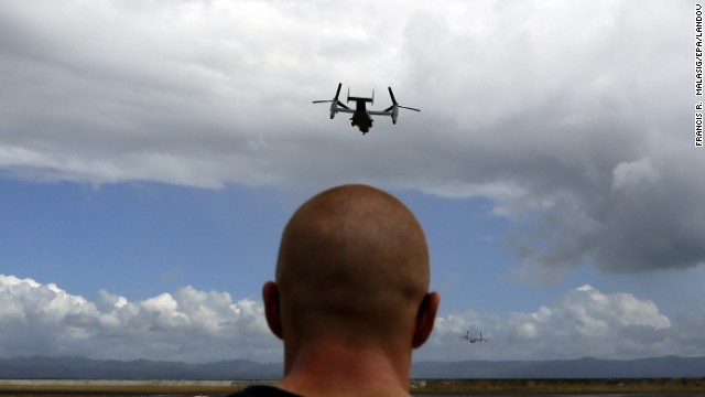 A U.S. aircraft flies above the Tacloban airport as a U.S. Marine watches November 16. 
