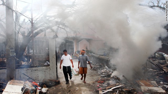 Men walk through smoke as they burn debris from a Tacloban church on November 16.
