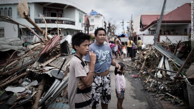 Survivors of the typhoon stand in a Tanauan street partially blocked by debris November 16.