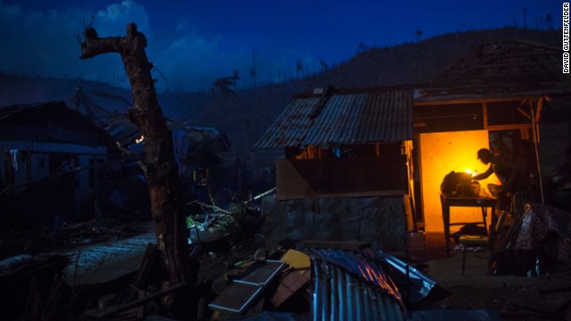 A survivor cooks dinner in front of his damaged home in the village of Marabut, Samar Island, on Friday, November 15.