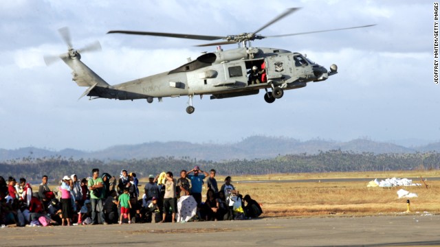 Evacuees wait to board military aircraft while a U.S. Navy helicopter takes off November 16 in Tacloban.