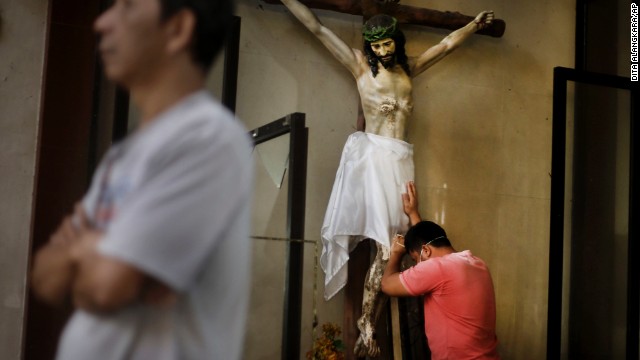 A man leans against a statue of the Crucifixion before a Mass at Santo Nino Church in Tacloban on November 17.
