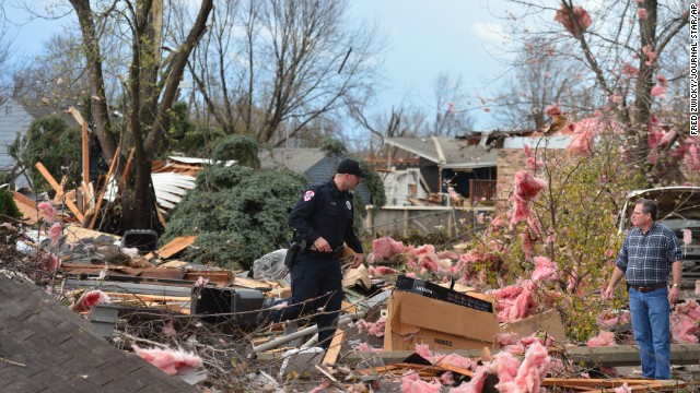 A police officer talks with a resident in Pekin after a tornado touched down in the area on November 17.