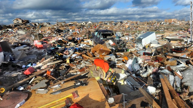 A firefighter, in lower center of photo, peers down into the home of a colleague whose home was destroyed when a tornado swept through Washington, Illinois, on November 17. 