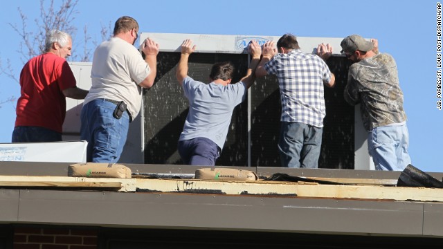 Volunteers try to reposition the HVAC unit on top of Heritage Primary Elementary School in Wentzville, Missouri, on November 17. Board members, staff and teachers came to the school to help with the cleanup after a storm tore off parts of the roof. Wentzville is about 40 miles west of St. Louis.