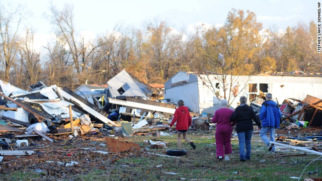 An elderly woman is escorted through tornado debris in Brookport, Illinois, on November 17.