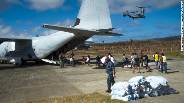 Filipinos board an HC-130 Hercules airplane as U.S. sailors carry relief supplies November 17 in Guiuan.