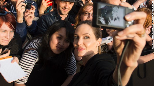 Actress Angelina Jolie takes a photo of herself with a fan's camera at the Paris premiere of "World War Z."