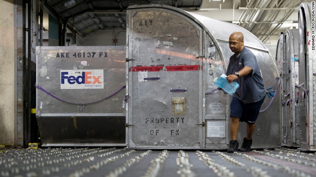 A FedEx worker moves containers full of packages at the cargo facility.