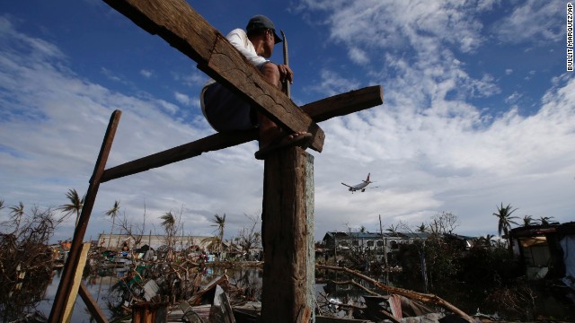 An airplane lands in Tacloban as Antonio Lacasa rebuilds his house on Thursday, November 21. 