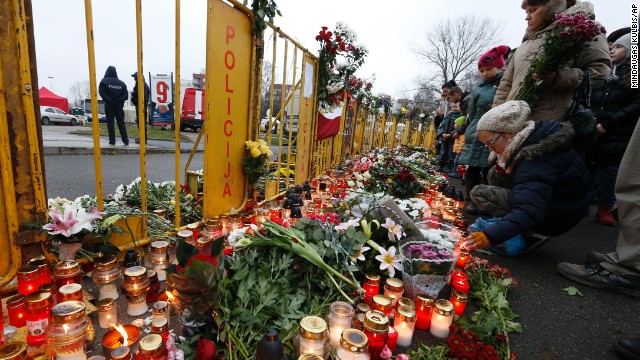 People place flowers and light candles in front of the Maxima supermarket in Riga, Latvia, on Saturday, November 23, two days after dozens of people reportedly died in a roof collapse. Riga Mayor Nils Usakovs said authorities suspect building materials stored on the roof caused it to collapse Thursday. 