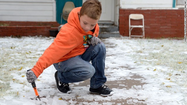 Phillip Miller, 8, uses a hammer to break up the ice on the walkway in front of his family's home in Odessa, Texas, on November 24.