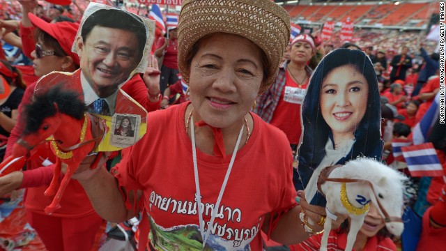 Thai pro-government 'red shirts' hold pictures of Thaksin and Yingluck Shinawatra as she gather at Rajamangala Stadium in Bankok Sunday.