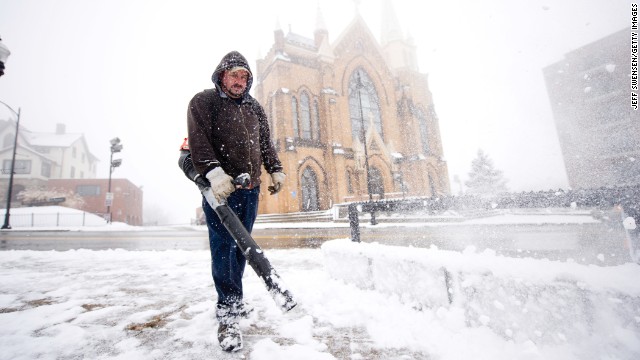 Mark Swigart uses a leaf blower to remove snow from the sidewalks November 26 in Pittsburgh.