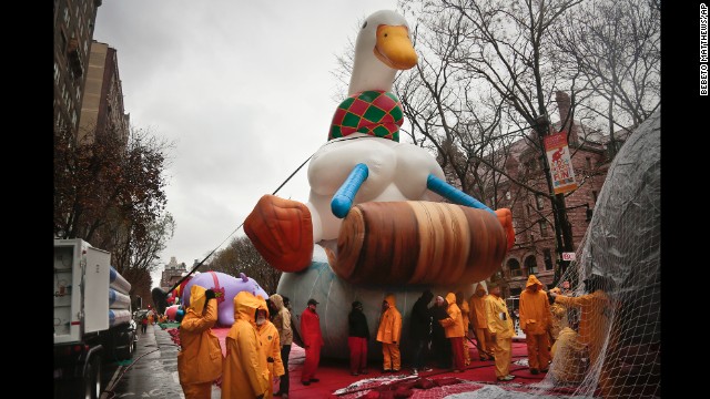 Technicians wear rain suits while inflating the Aflac balloon.