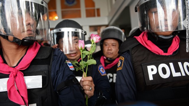 A Thai riot policeman holds flowers which were offered to him by opposition protesters during a rally at a government complex in Bangkok on November 27, 2013.