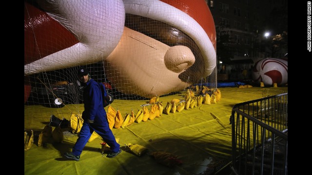 Sandbags hold the Elf on a Shelf balloon down as workers prepare in hopes the balloons will get to fly. 