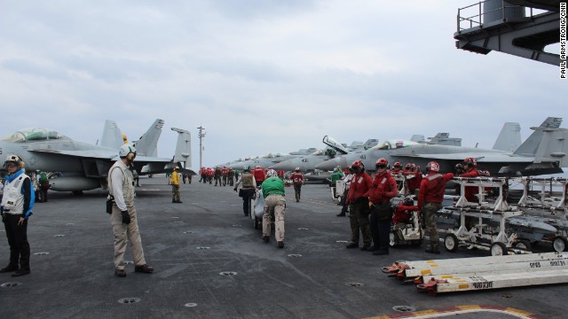 The carrier's flight deck crew -- wearing colored vests according to the duties they perform -- are responsible for flight ops night and day.