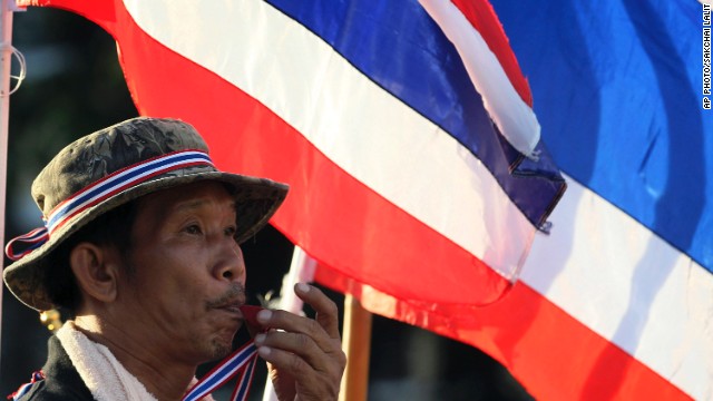 An anti-government protester blows a whistle in front of Thai flags during a rally at Bangkok's Democracy Monument on Friday, one day after the embattled Prime Minister Yingluck Shinawatra survived a no-confidence vote in parliament.