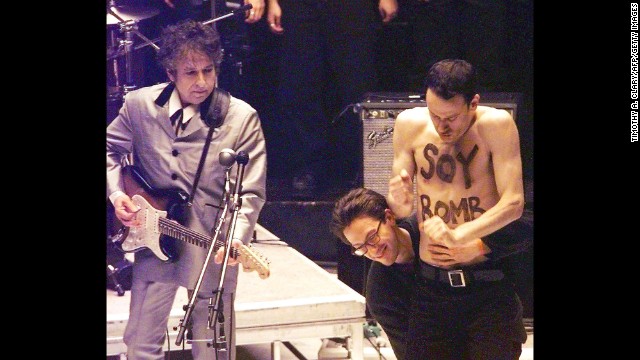 Performance artist Michael Portnoy is taken off stage during Dylan's performance at the Grammy Awards in 1998. Portnoy had been hired as part of the background dancers for the performance, but his shirtless interruption was not planned and he was carted off stage.