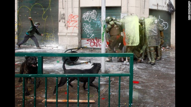 <strong>April 11:</strong> A protester aims a rock at a huddle of shielded riot police after students held a march demanding free education in Santiago, Chile.