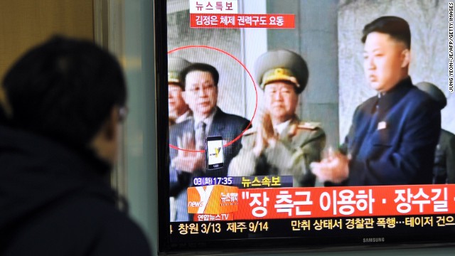 A S. Korean man watches the news about the alleged dismissal of Jang Sung-taek (left), uncle of Kim Jong Un (right).