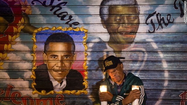 An artist who goes by the name Franco the Great stands beneath a Mandela mural that he painted in New York's Harlem neighborhood more than 15 years ago. He later added Obama to the mural.