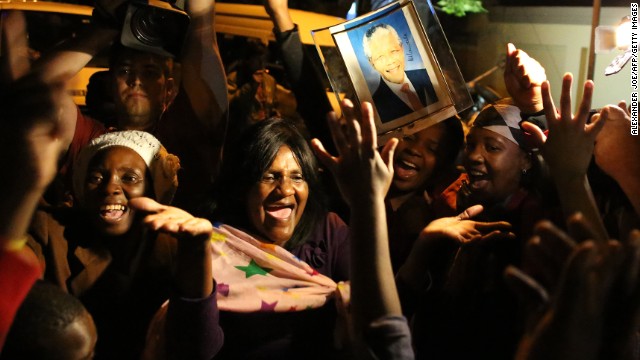 South Africans hold pictures of former South African president Nelson Mandela as they pay tribute following his death in Johannesburg on Friday, December 6.