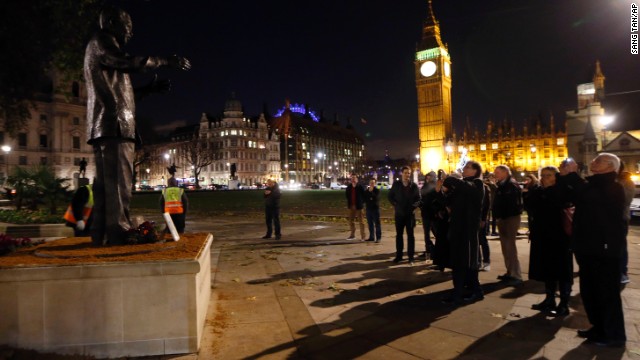 A small crowd gathers in front of a statue of Nelson Mandela at Parliament Square in London, on December 6. 