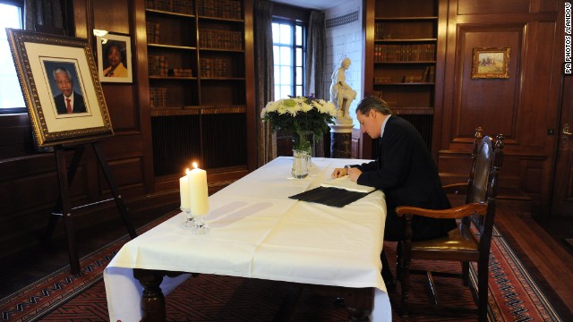 British Prime Minister David Cameron signs the book of condolence at the South African Embassy in central London following the announcement of Mandela's death.