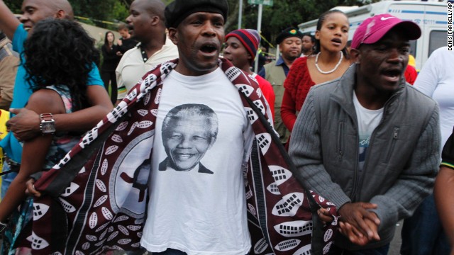 A man wearing a T-shirt with a portrait of Mandela leads a group of mourners as they sing and dance outside Mandela's Johannesburg home on December 6.