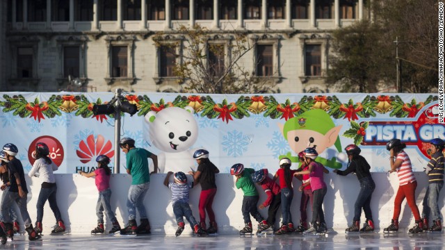 Young skaters in Guatemala City, Guatemala, hold on to a wall as they skate on an ice ring installed at Constitution Square on December 4.