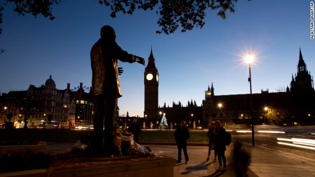 Early morning commuters stand in silence beside a statue of Mandela on December 6 in Parliament Square in London.