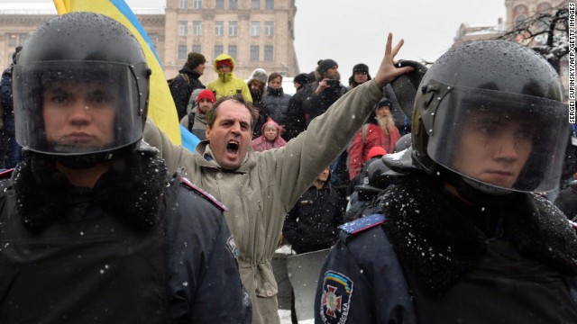 A protester shouts behind riot police standing guard in Independence Square in Kiev on Monday, December 9. 