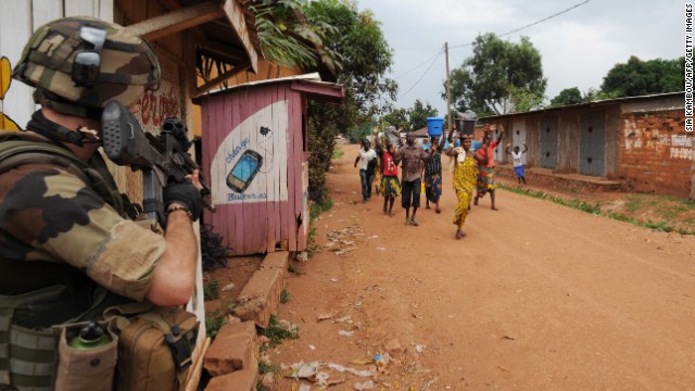 People walk by a French soldier standing guard during a disarmament operation in Bangui on December 9.