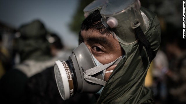 A demonstrator wearing a gas mask looks on outside a government building in Bangkok on December 9.