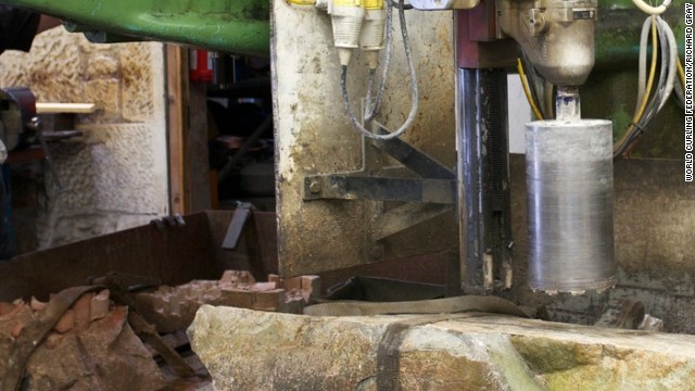 A machine cores a hole into the base of the curling stone, in this case the common green stone, and a mold of separate granite is added to make an even higher quality product.