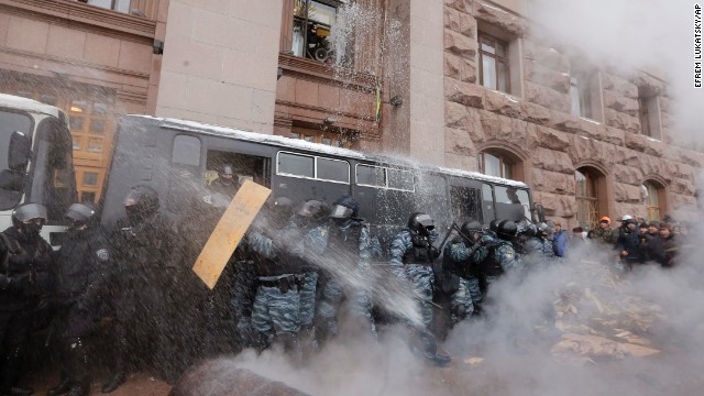 Riot police officers block the entrance of City Hall as protesters pour water from windows and throw smoke grenades at them on December 11.