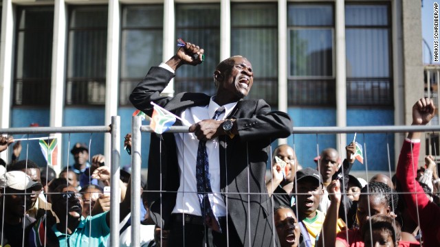 A cheering man climbs up a fence after the casket of Mandela passed on its way to the Union Buildings on December 13.