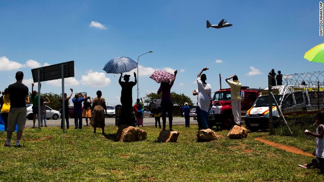 People wave at the aircraft carrying the casket of Mandela as it takes off from Waterkloof air base on the outskirts of Pretoria, South Africa.