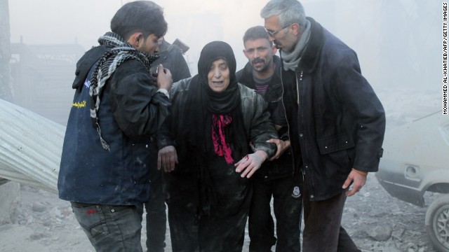 Syrians help a wounded woman following airstrikes in Aleppo on December 15.
