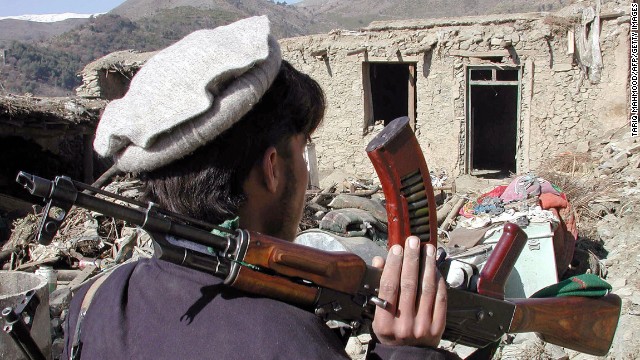 A Pakistani tribesman carries an AK-47 assault rifle after an air strike in Damadola, Pakistan, in 2006.